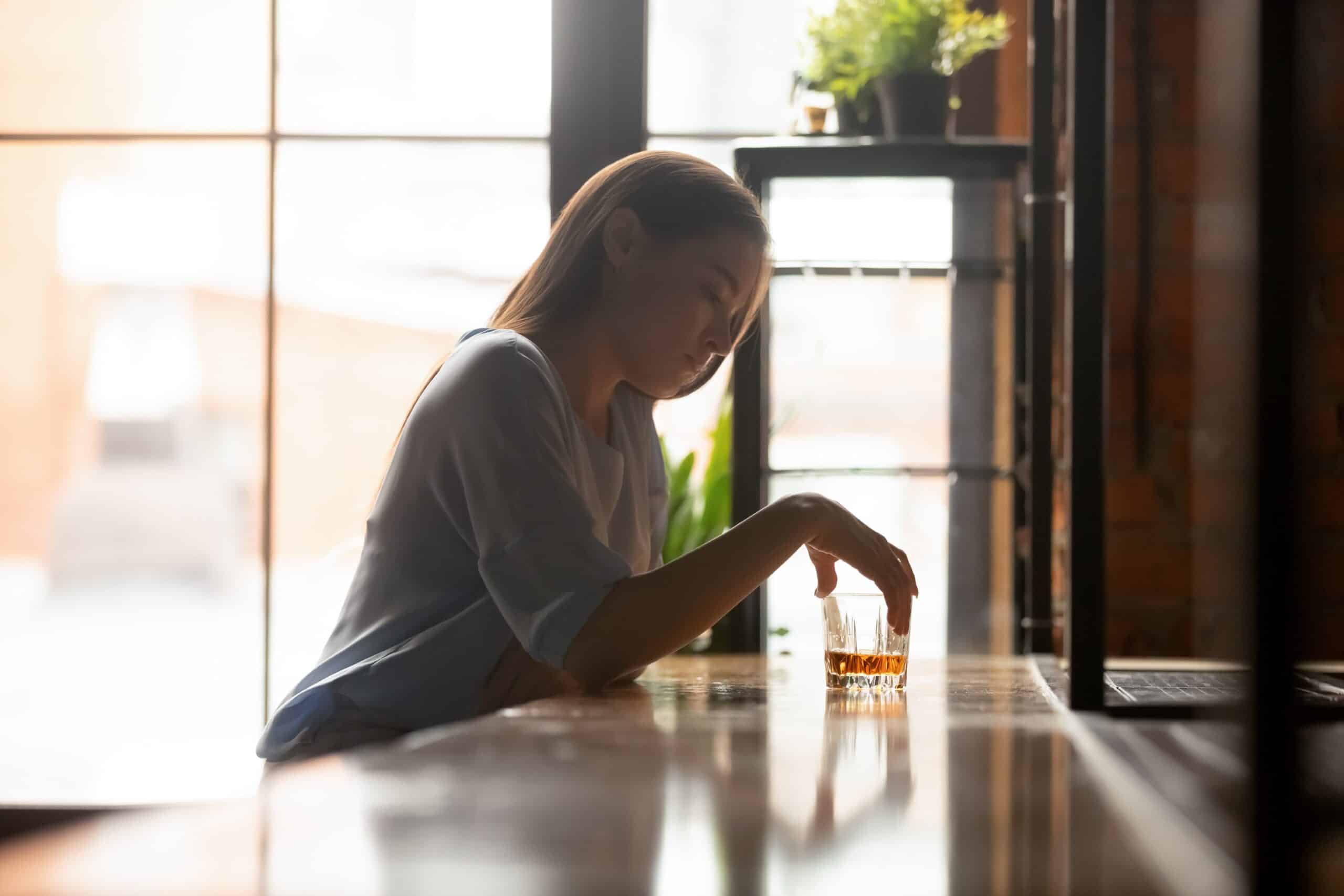 woman with an alcohol addiction sits at a bar