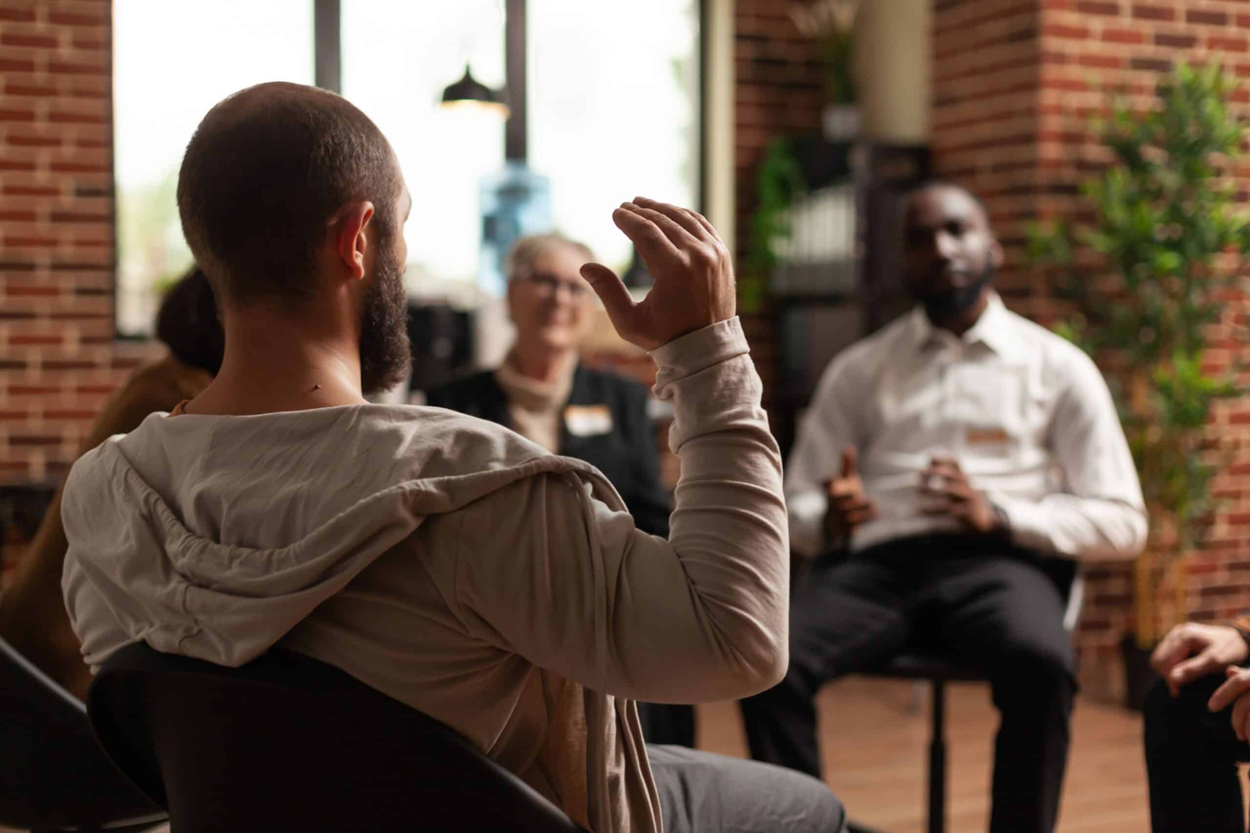 A man discusses behavioral addiction risk factors during a group therapy treatment session.