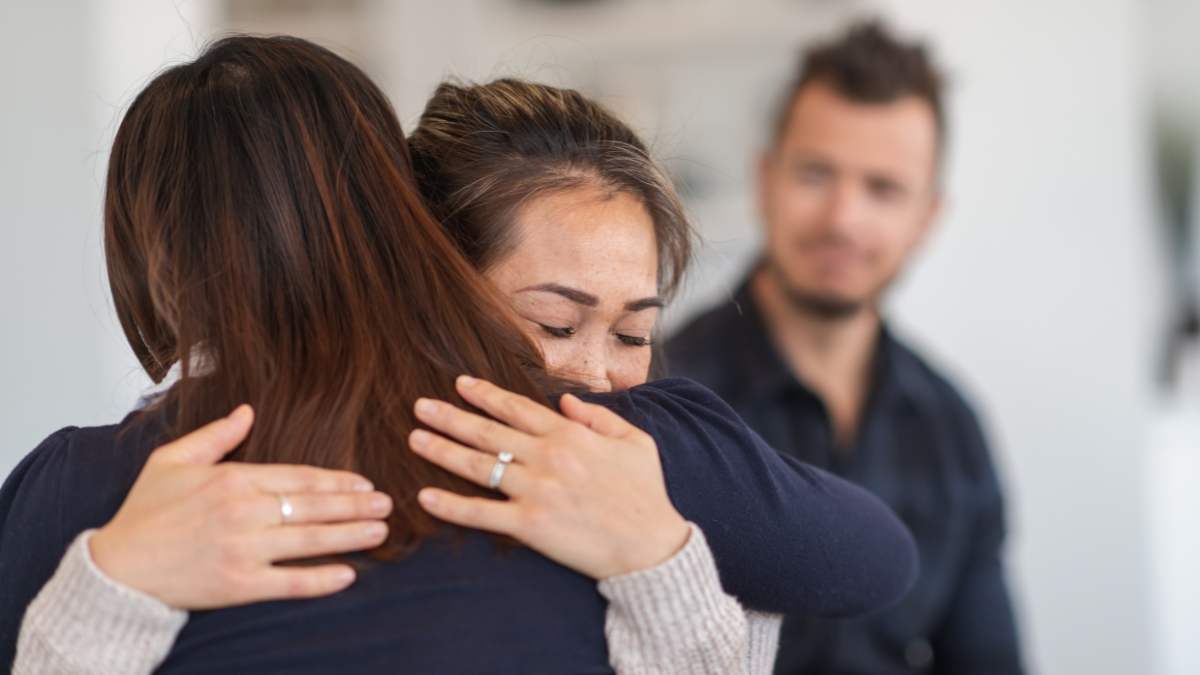 Woman struggling with substance use disorder hugging loved one during group therapy in Pompano Beach. 