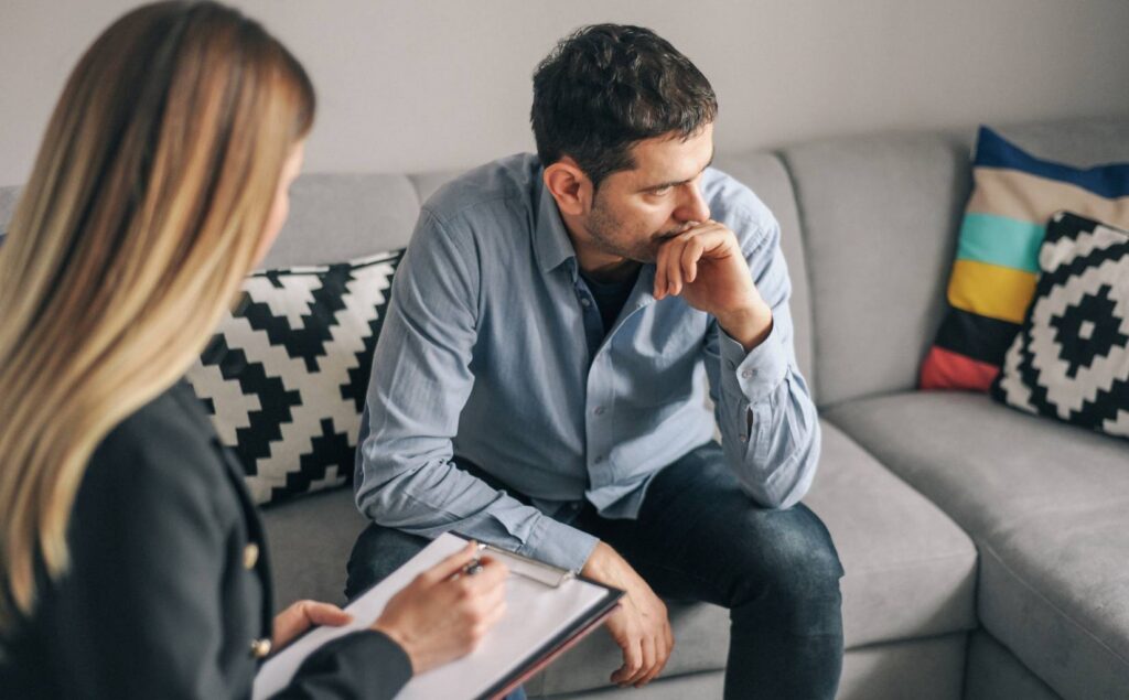 Man sitting quietly in therapy, opening up about sobriety fatigue.